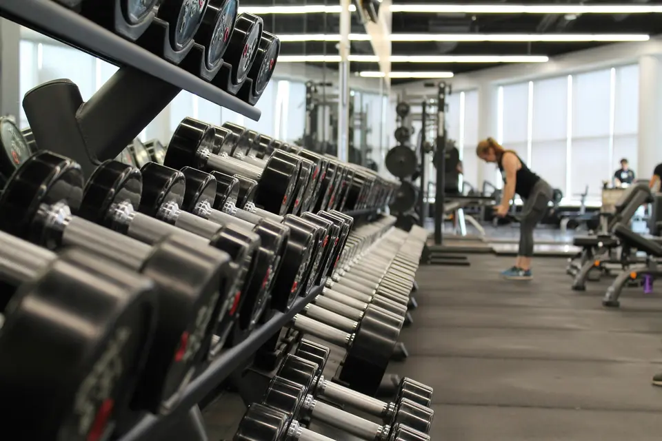 Dumbbell rack in a gym with people training in the background.
